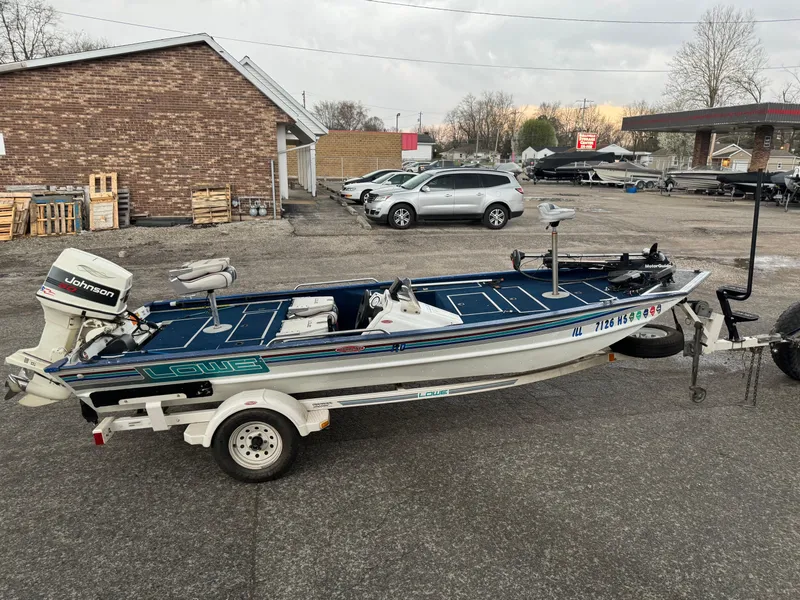 The Image of 1994 Lowe 170 boat with Johnson outboard motor on trailer, parked in a lot. - 1