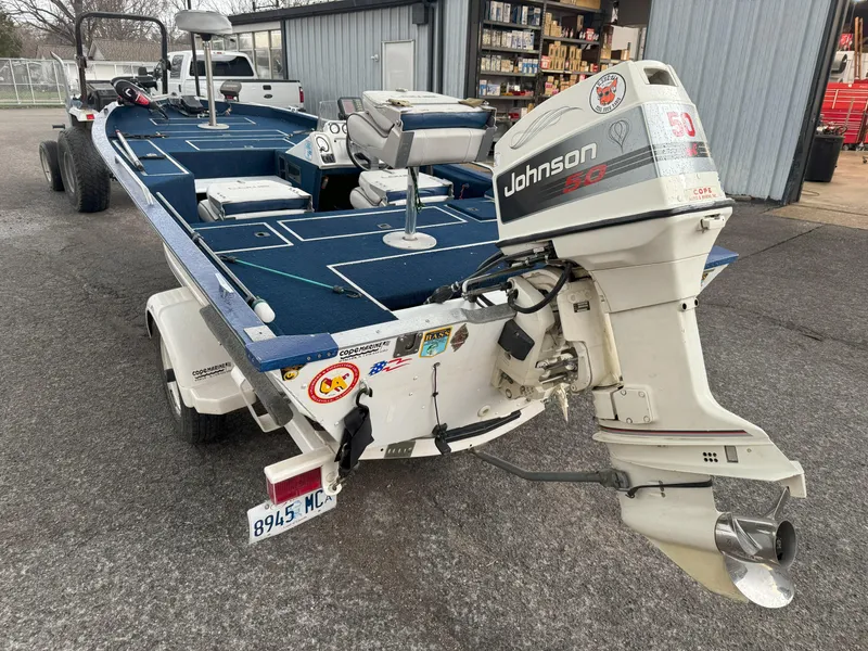 Slide: The Image of 1994 Lowe 170 boat with Johnson outboard motor, parked on a trailer near a garage. - 4