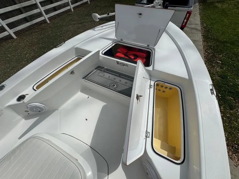 Slide: The Image of 2011 BlackJack 224 boat deck with open storage compartments and life jackets. - 17