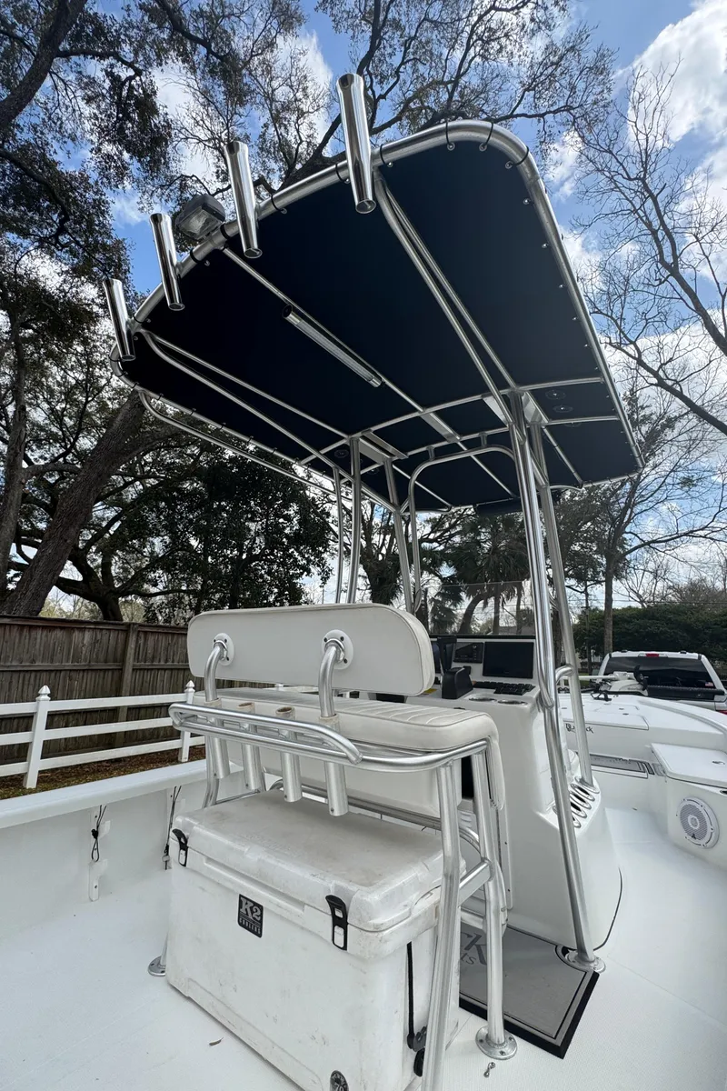 Slide: The Image of 2011 BlackJack 224 boat with T-top and seating, set against a wooded backdrop. - 24