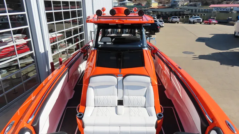 Slide: The Image of 2023 Nor-Tech 450 boat with vibrant orange exterior and white seating, docked at a marina. - 26