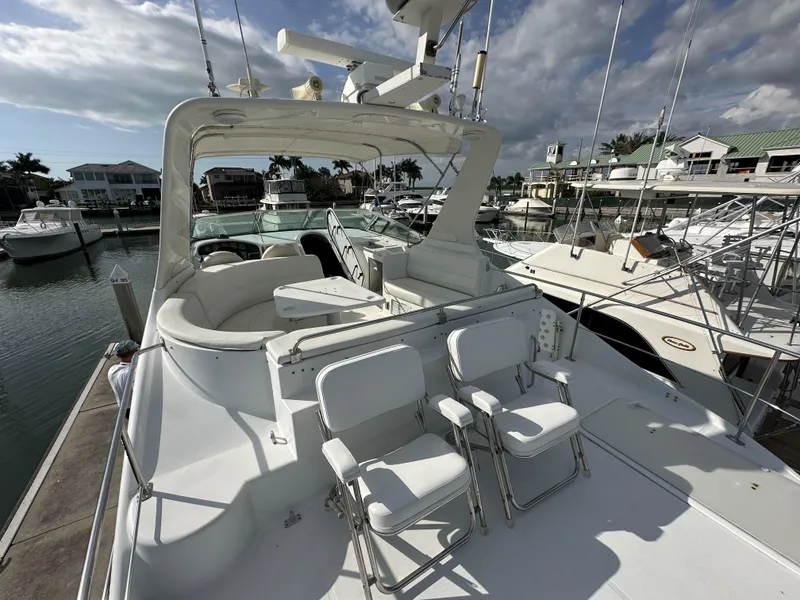 Slide: The Image of 1999 Carver 530 Voyager Pilothouse yacht docked at marina, featuring spacious deck and seating. - 4