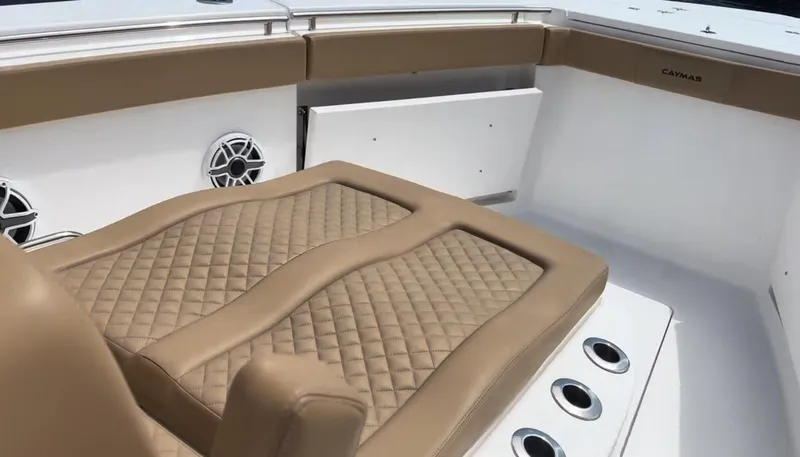 Slide: The Image of 2023 Caymas 341 CC boat interior with tan quilted seating and built-in speakers. - 12
