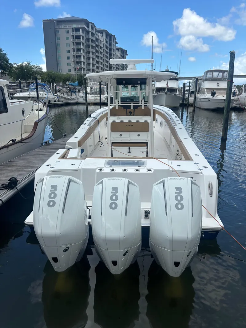 Slide: The Image of 2023 Caymas 341 CC boat docked with triple outboard engines, marina background. - 3
