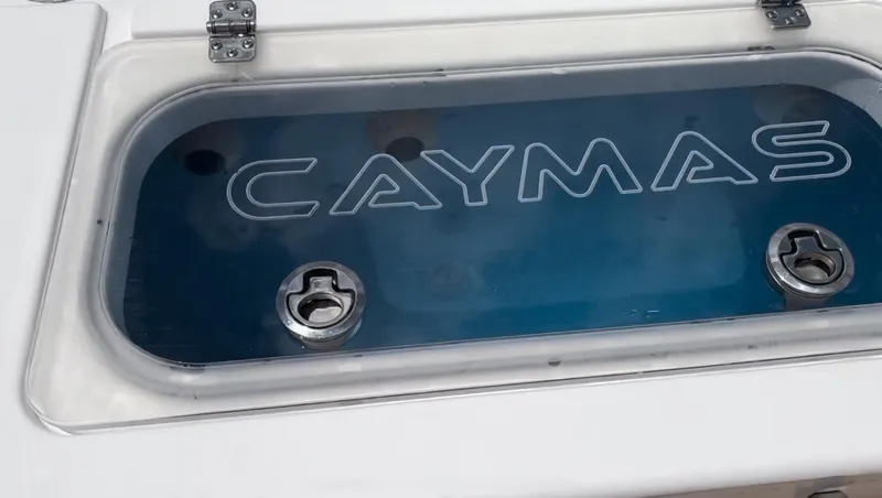 Slide: The Image of 2023 Caymas 341 CC livewell with logo, featuring secure latches and clear lid. - 36