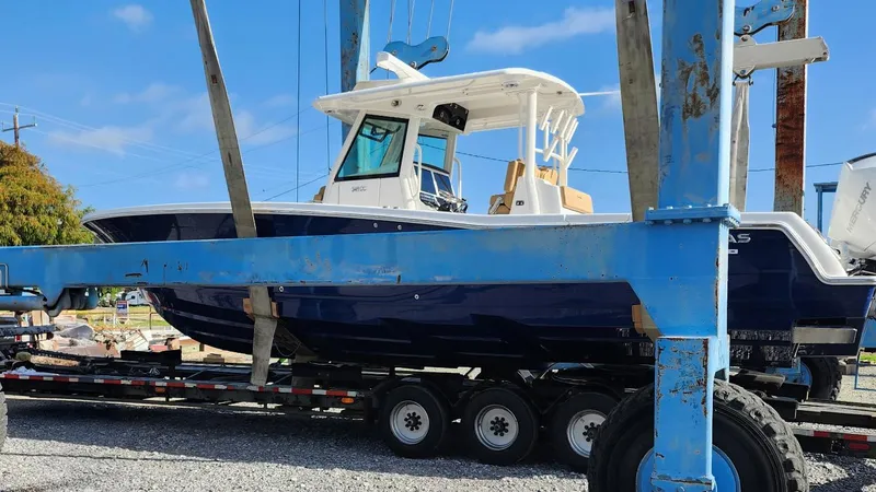 Slide: The Image of 2023 Caymas 341 CC boat on trailer, blue hull, white cabin, outdoor setting. - 6