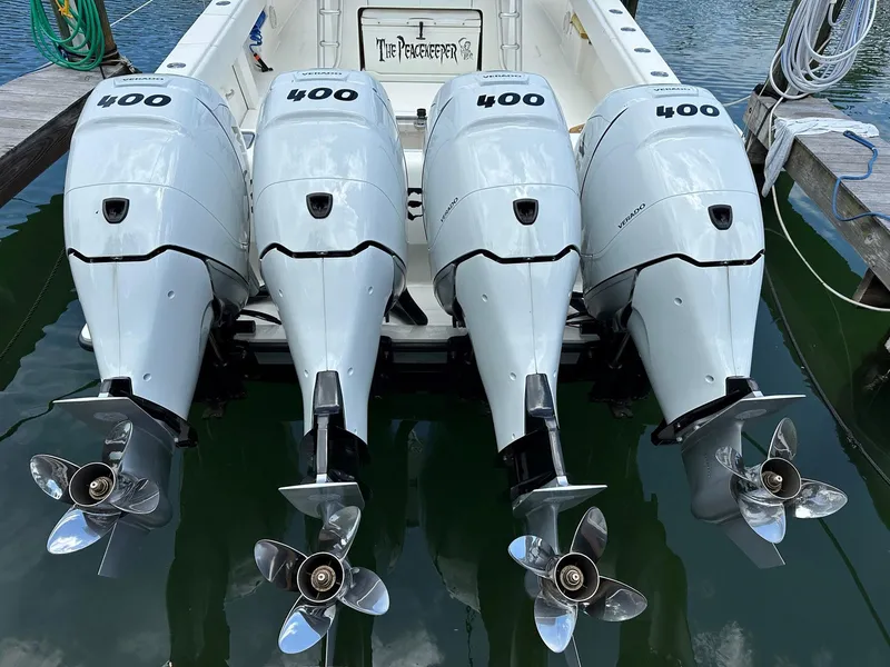 Slide: The Image of Four powerful outboard motors on a 2018 SeaVee 390Z boat, docked on calm water. - 24