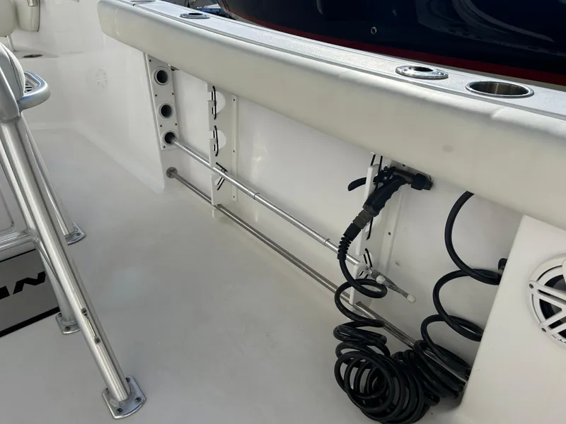 Slide: The Image of 2020 Sportsman Open 232 Center Console boat interior with rod holders and coiled cable. - 23