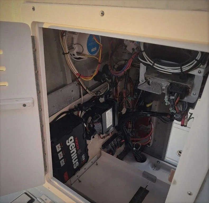Slide: The Image of Electrical compartment of a 1992 Bay Hawk 204 boat, featuring wiring and a battery charger. - 17