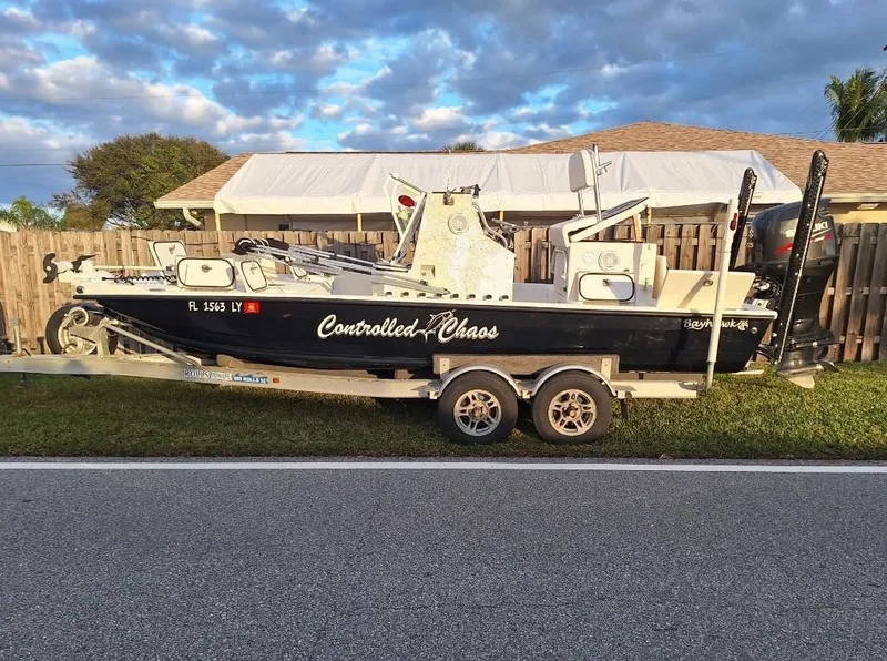 Slide: The Image of Bay Hawk 204 boat on trailer, labeled "Controlled Chaos," parked beside a wooden fence. - 4