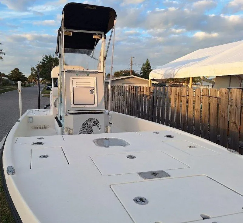 Slide: The Image of Bay Hawk 204 boat, 1992 model, with a center console and canopy, parked near a wooden fence. - 8