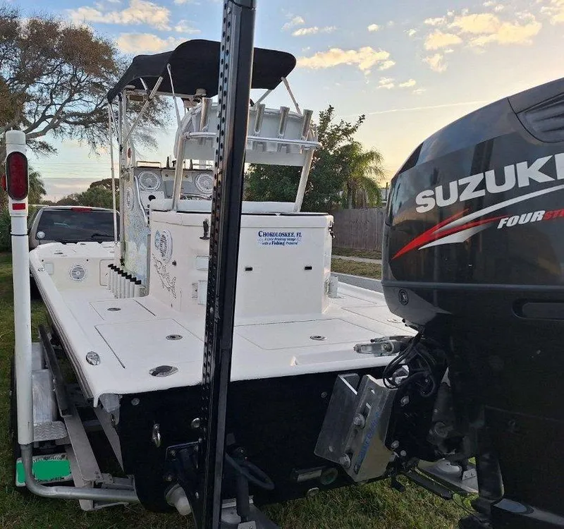 Slide: The Image of Bay Hawk 204 boat with Suzuki engine, parked on trailer, under a clear sky. - 9