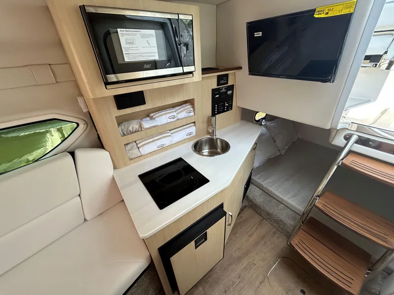 Slide: The Image of 2025 Regal 26 XO boat interior with kitchenette, microwave, sink, and stairs. - 20