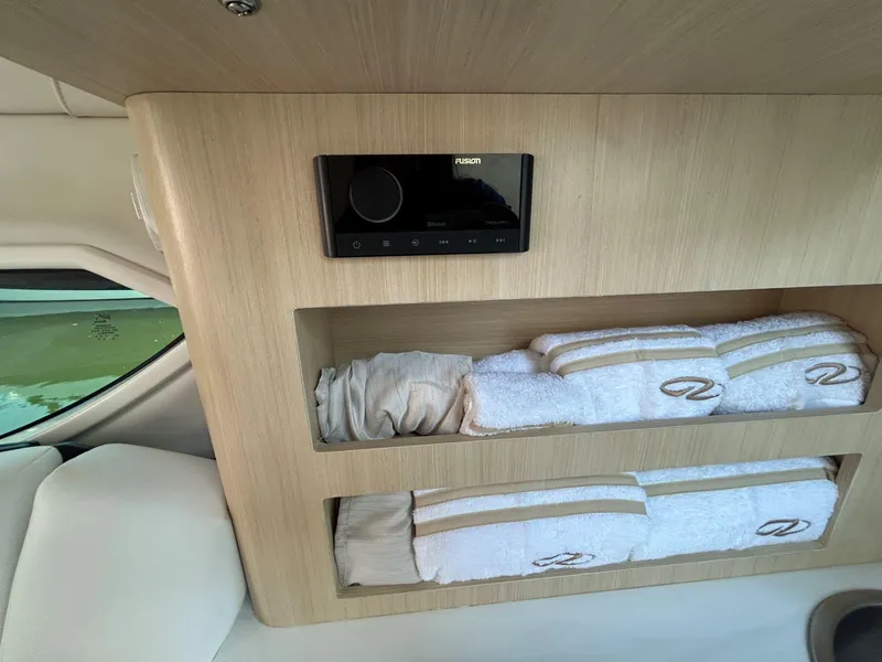 Slide: The Image of Interior of 2025 Regal 26 XO boat with shelves and towels, featuring a Fusion audio system. - 23
