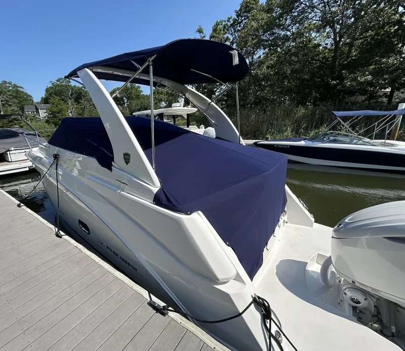 Slide: The Image of 2025 Regal 26 XO boat docked, covered with a navy blue canopy. - 26