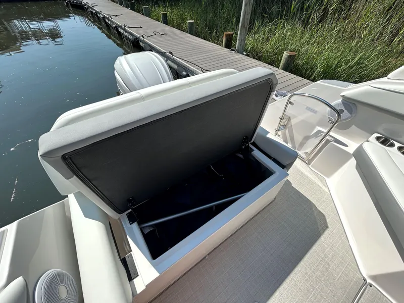 Slide: The Image of 2025 Regal 26 XO boat with open storage compartment by a dock. - 7