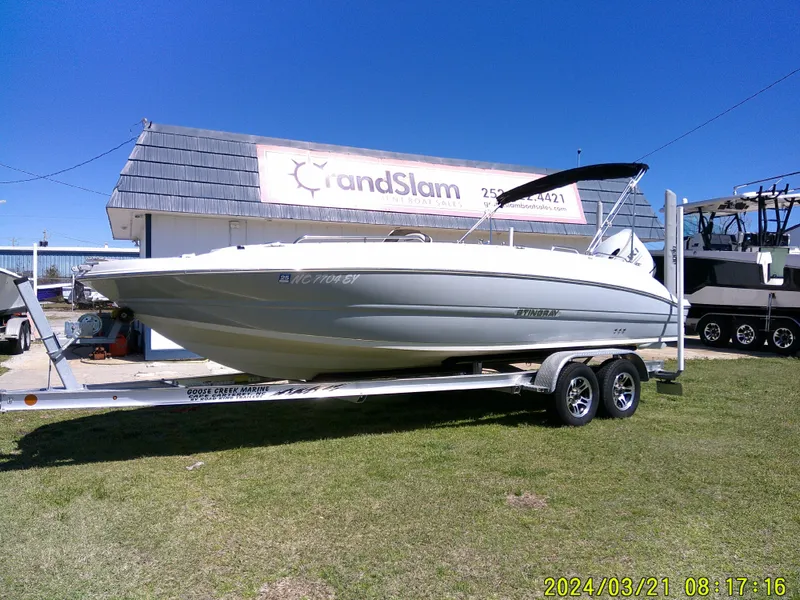 The Image of 2022 Stingray 212SC boat on trailer, parked outdoors under clear blue sky. - 0