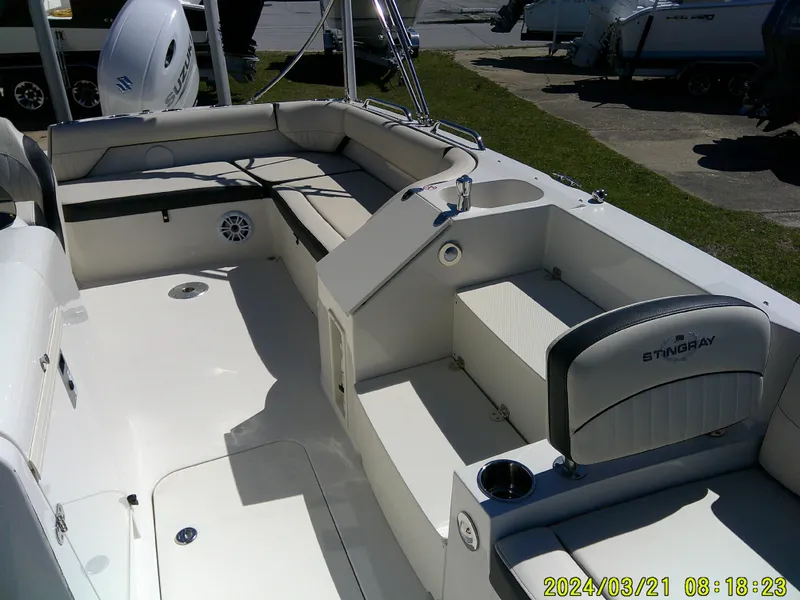 Slide: The Image of 2022 Stingray 212SC boat interior with seating and motor, photographed outdoors. - 14