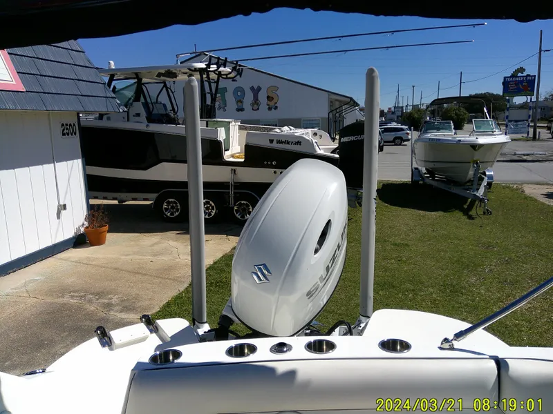 Slide: The Image of 2022 Stingray 212SC boat with Suzuki outboard motor, parked near other boats. - 22