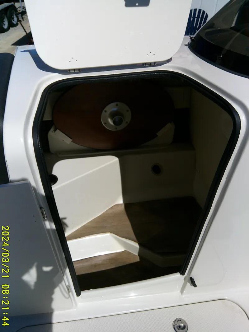 Slide: The Image of 2022 Stingray 212SC boat interior cabin with open hatch, showcasing compact design. - 27