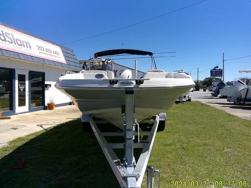 Slide: The Image of 2022 Stingray 212SC boat on trailer outside dealership under clear blue sky. - 5
