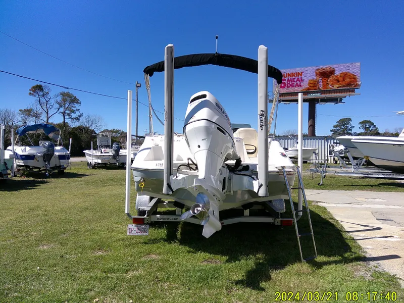 Slide: The Image of 2022 Stingray 212SC boat on trailer, parked on grass, with clear blue sky background. - 7