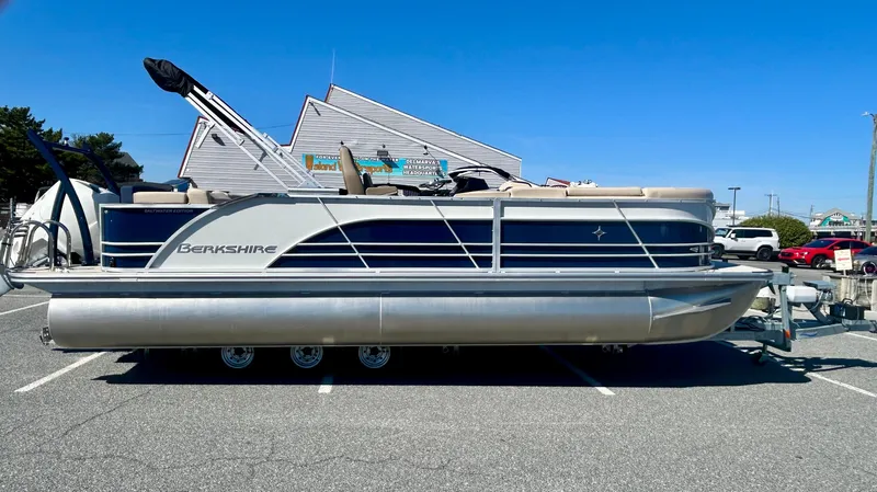 The Image of 2025 Berkshire 23CL STS 3.0 pontoon boat parked in a lot under clear blue sky. - 0