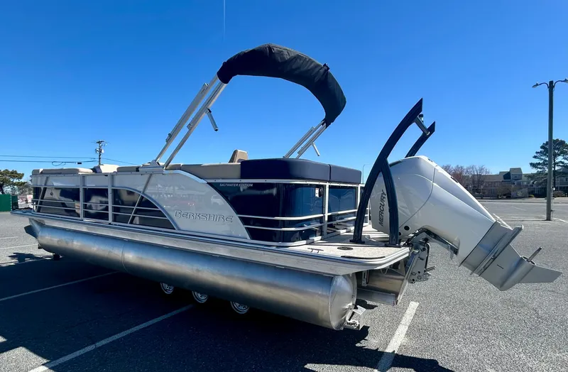 Slide: The Image of 2025 Berkshire 23CL STS 3.0 pontoon boat with canopy and outboard motor in parking lot. - 1