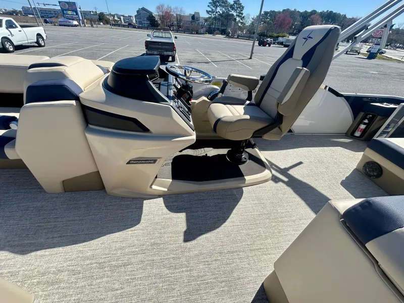 Slide: The Image of 2025 Berkshire 23CL STS 3.0 boat interior with helm and seating in a parking lot. - 12