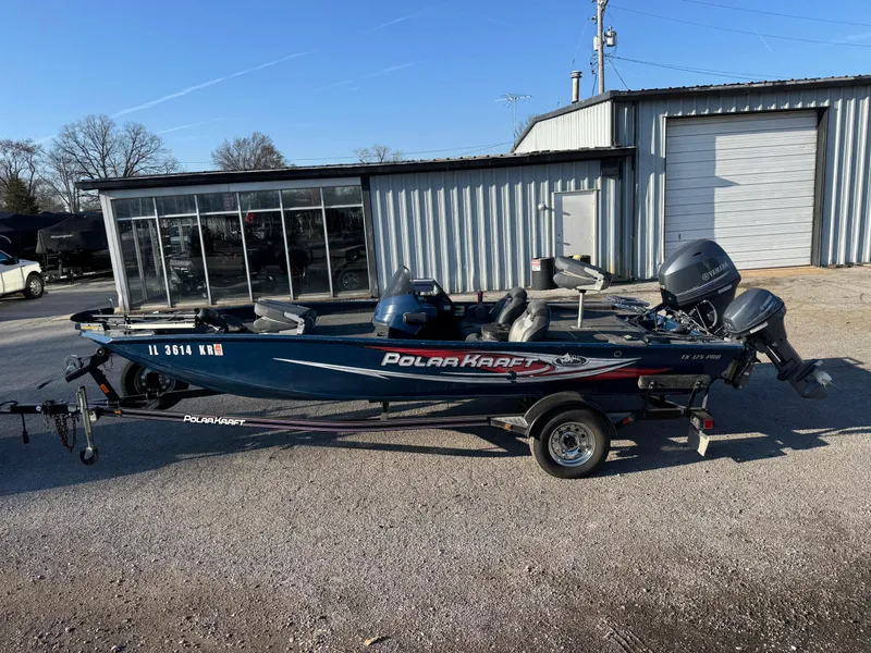 Slide: The Image of 2014 Polar Kraft Bass TX 175 Pro boat parked outside a metal building. - 0