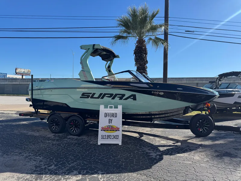 The Image of 2025 Supra SL 450 boat on trailer, displayed outdoors with palm tree background. - 1