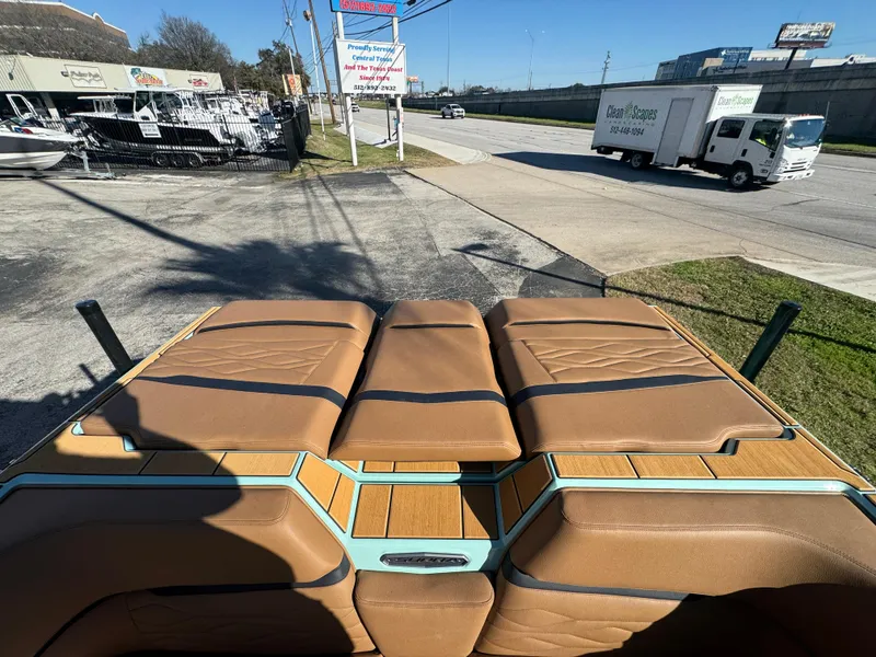 Slide: The Image of 2025 Supra SL 450 boat interior with tan leather seats and wood accents, parked outdoors. - 18