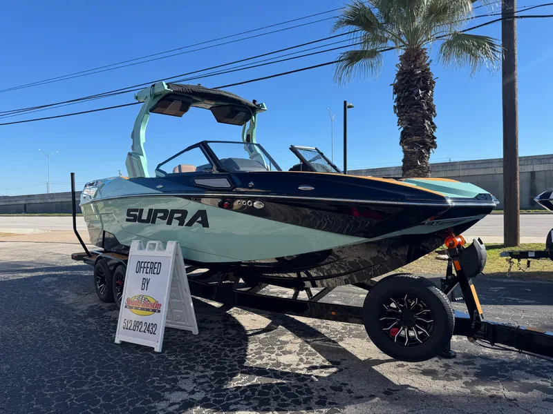 Slide: The Image of 2025 Supra SL 450 boat on trailer, displayed outdoors with palm tree background. - 2
