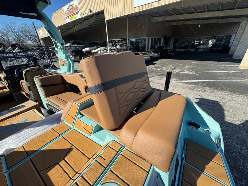 Slide: The Image of 2025 Supra SL 450 boat interior with brown seating and teal accents, outside a dealership. - 21