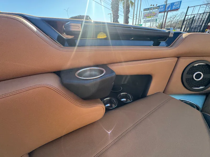 Slide: The Image of 2025 Supra SL 450 interior with tan leather, cup holders, and speaker detail. - 49