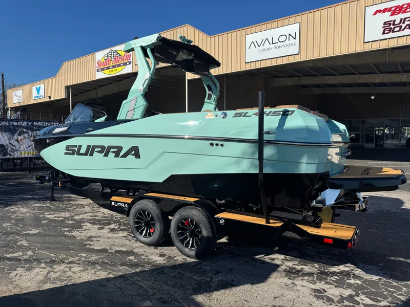 Slide: The Image of 2025 Supra SL 450 boat in mint green on a trailer outside a dealership. - 7