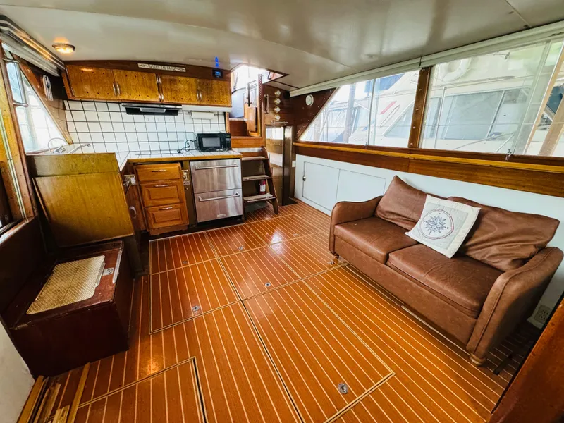 Slide: The Image of 1965 Chris-Craft 38 Constellation interior with wood flooring, kitchenette, and brown sofa. - 10