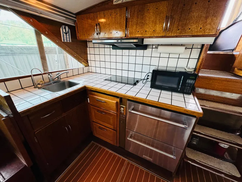Slide: The Image of 1965 Chris-Craft 38 Constellation kitchen with wood cabinets, tiled countertops, and modern appliances. - 13