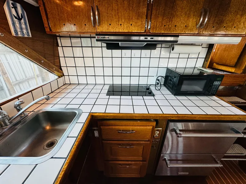 Slide: The Image of 1965 Chris-Craft 38 Constellation kitchen with tiled countertop, sink, and microwave. - 14