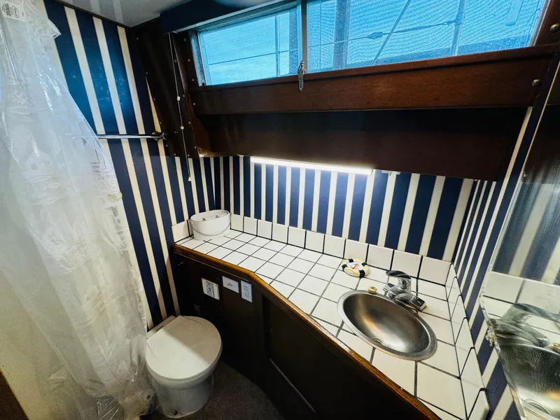 Slide: The Image of 1965 Chris-Craft 38 Constellation bathroom with striped walls, tiled countertop, and stainless steel sink. - 18