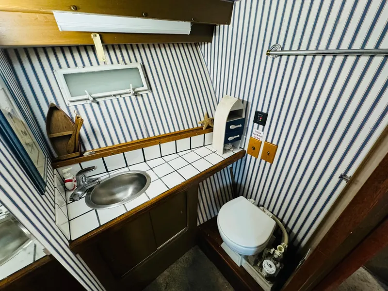 Slide: The Image of 1965 Chris-Craft 38 Constellation bathroom with striped wallpaper, sink, and toilet. - 20