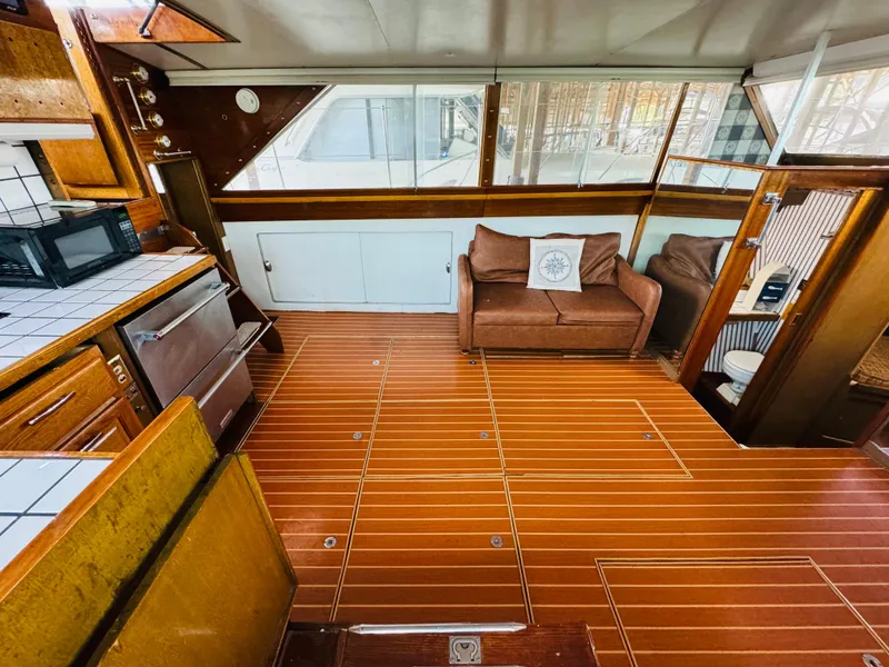 Slide: The Image of 1965 Chris-Craft 38 Constellation interior with wood flooring, sofa, and kitchen area. - 7