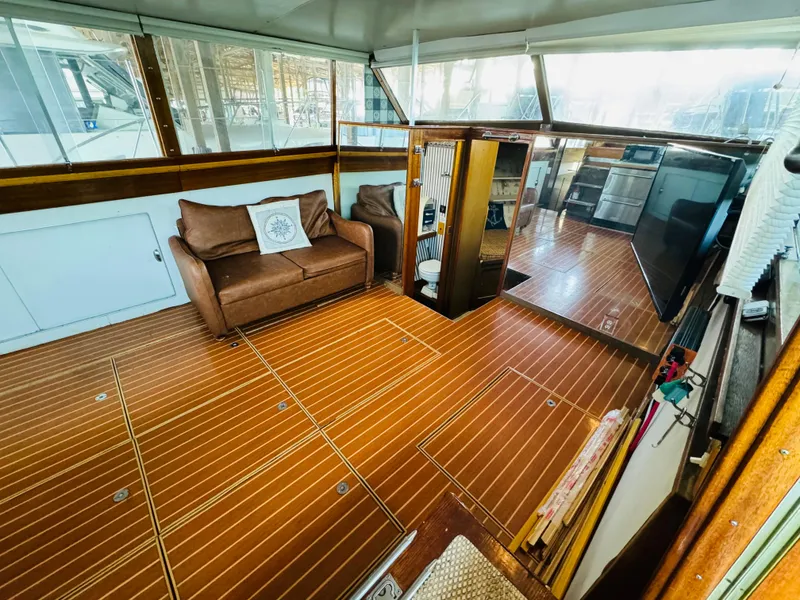 Slide: The Image of 1965 Chris-Craft 38 Constellation interior with wood flooring, sofa, and large windows. - 9