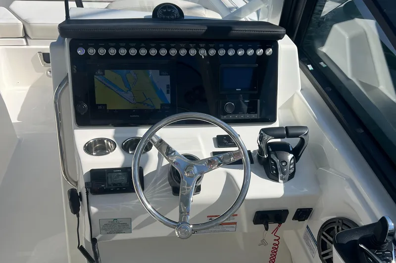 Slide: The Image of 2024 World Cat 260 DC-X boat dashboard with steering wheel, navigation system, and controls. - 10