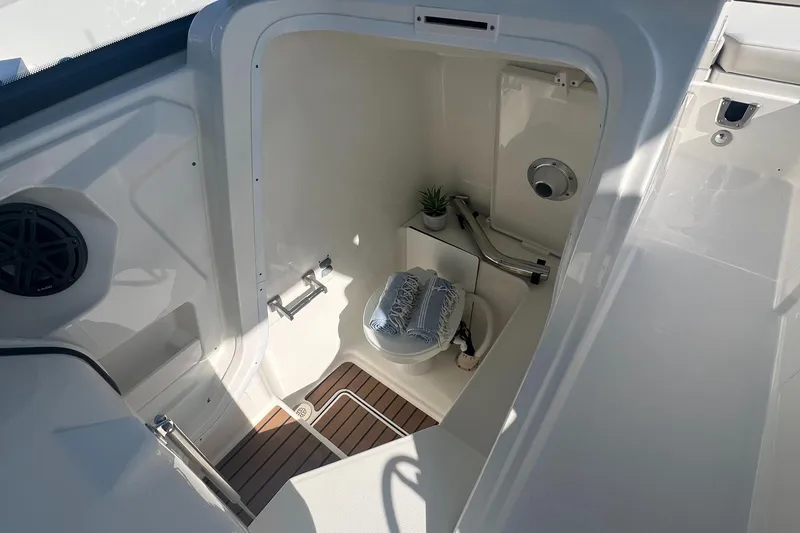 Slide: The Image of 2024 World Cat 260 DC-X boat interior with compact marine toilet and wooden flooring. - 15