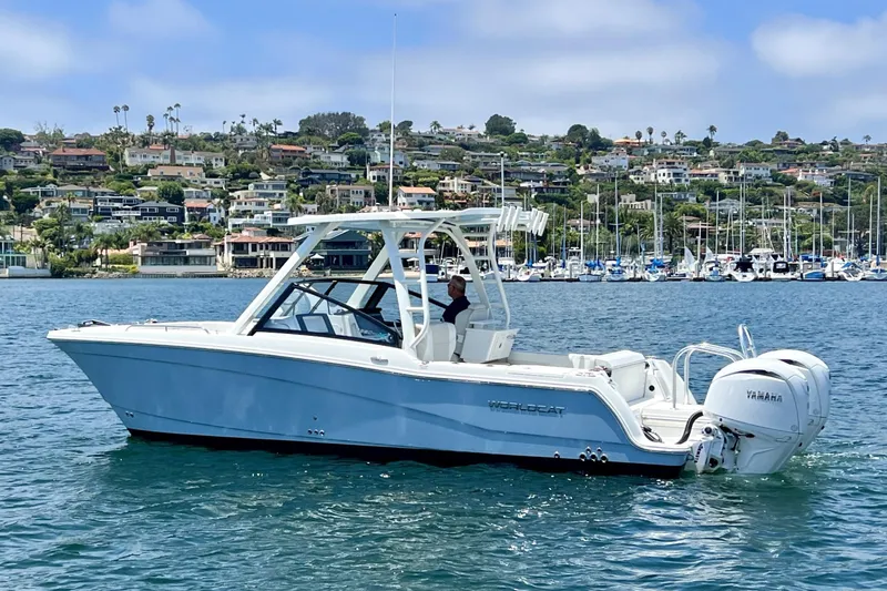 Slide: The Image of 2024 World Cat 260 DC-X boat cruising on a scenic waterfront with houses and marina. - 55