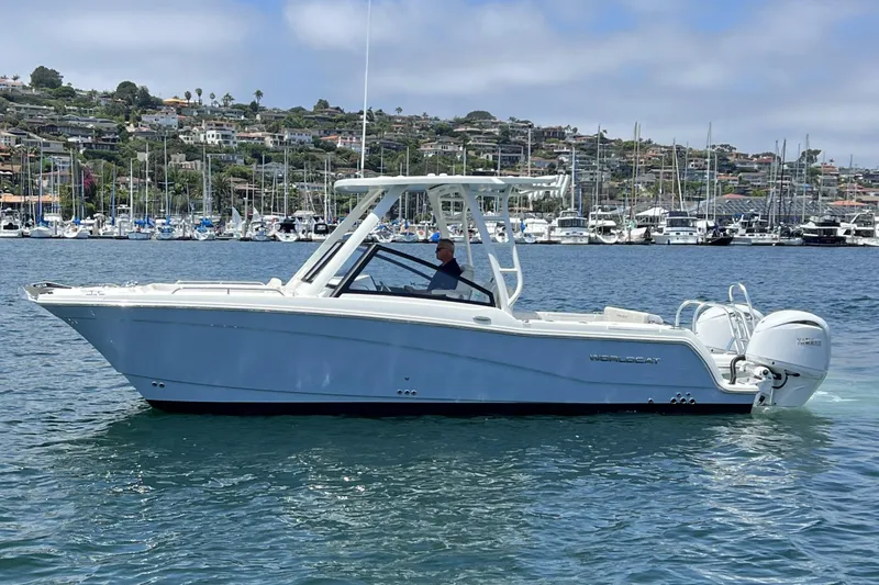 Slide: The Image of 2024 World Cat 260 DC-X boat cruising on a scenic waterfront with houses and marina. - 56
