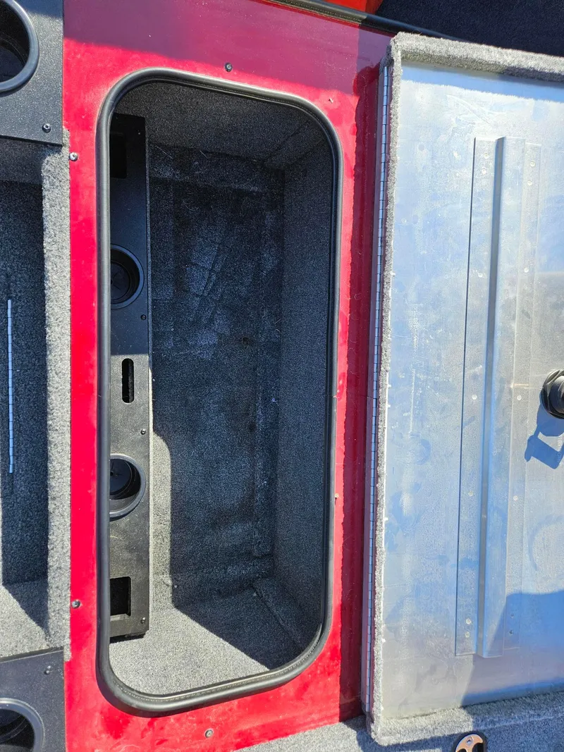 Slide: The Image of 2022 Tracker Pro Team 195 TXW Tournament Edition boat storage compartment, open lid, red interior. - 16