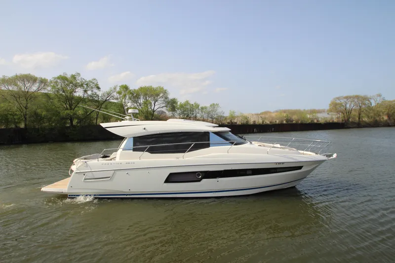 Slide: The Image of 2019 Prestige 460S yacht cruising on a calm river with trees in the background. - 0