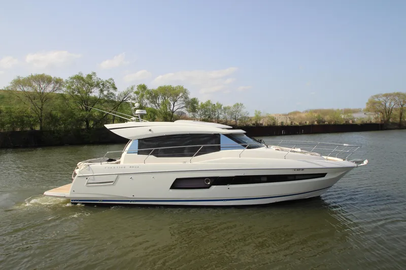 Slide: The Image of 2019 Prestige 460S yacht cruising on a calm river with trees in the background. - 2